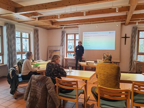 Die Teilnehmenden sitzen im Raum und blicken zur Präsentation an der Leinwand und zu unserem Referenten Johannes der neben der Leinwand steht