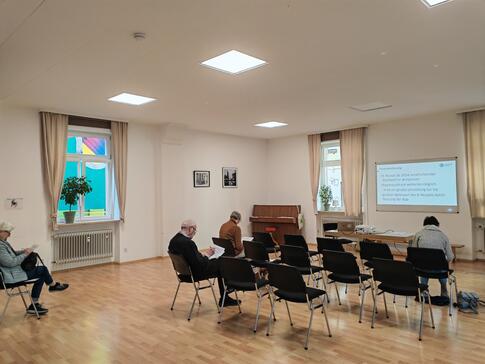 Die Teilnehmenden sitzen im Raum und schauen zur Präsentation an der Leinwand