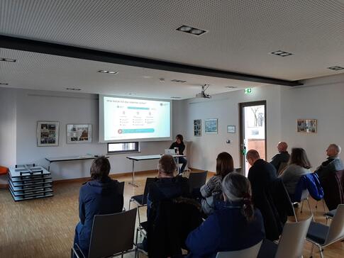 Die Teilnehmenden sitzen im Raum und schauen zur Präsentation an der Leinwand