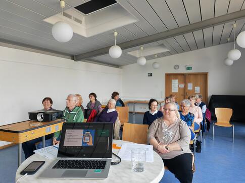 Die Teilnehmenden sitzen im Raum und schauen zur Präsentation an der Leinwand