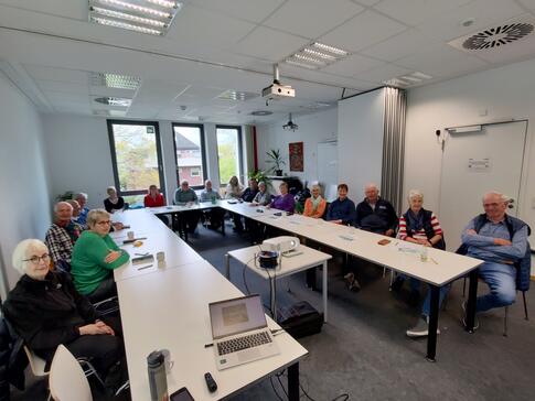 Rund 20 Damen und Herren sind in einem Raum des Familienzentrums in einer U-Form. Einige gucken in die Kamera.