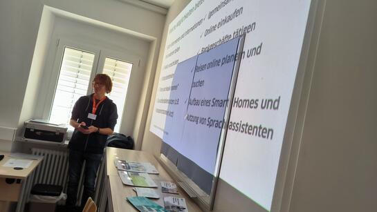 Referent Johannes steht vor einer auf die Wand projizierten Präsentation 