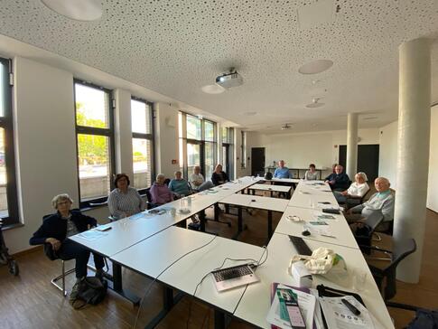 In einem Raum im Pattensener Rathaus sitzen über zehn Menschen an verschiedenen Tischen verteilt.