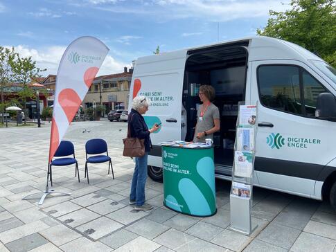 Eine Dame steht vor dem Infomobil und blickt zu Johannes