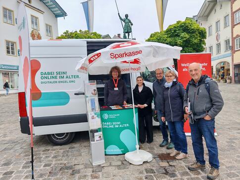 Johannes steht neben mehreren Personen vor dem Infomobil.