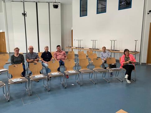In einem großen Veranstaltungssaal im Rathaus Wiedemar sitzen sechs Personen auf zwei Stuhlreihen und blicken nach vorne in die Kamera.