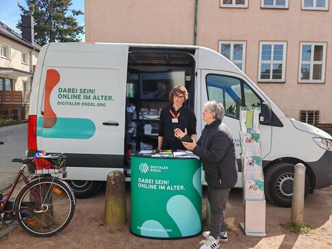 Eine Dame steht vor dem Infomobil und blickt zum Referenten Johannes 