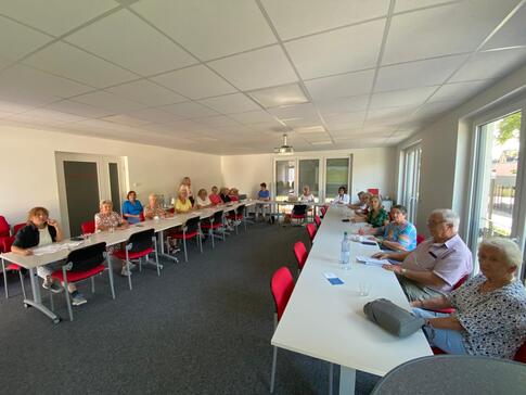 Im Weitwinkelmodus sind 16 Personen an Tischen in U-Form abgebildet. Die Menschen sind nur schwer zu erkennen, da sie klein auf dem Bild sind.