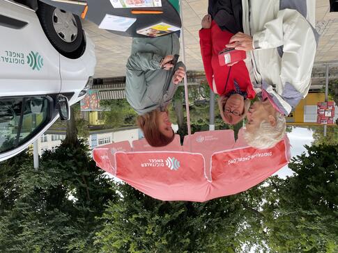 Theresa ber&auml;t zwei Seniorinnen vor dem Sonnenschirm links neben dem Infomobil.
