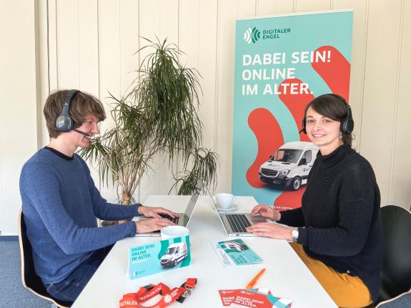 Monika und Johannes sitzen gemeinsam mit Laptop am Tisch
