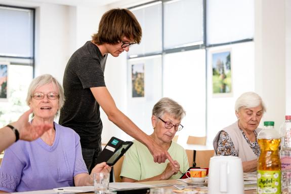 Junger Mann zeigt auf Smartphone einer älteren Frau.
