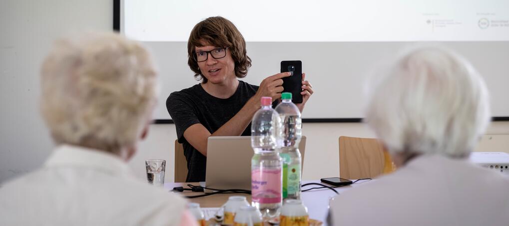 Junger Mann zeigt auf Smartphone