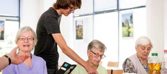 Junger Mann zeigt auf Smartphone einer älteren Frau. 