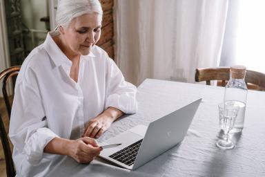 Frau schaut auf Laptop mit Karte in der Hand